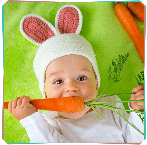 Photo d'un bébé avec un bonnet en forme d'oreille de lapin et mangeant une carotte